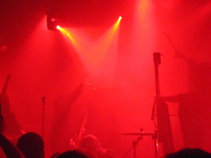a concert in a red lit room with three spotlights