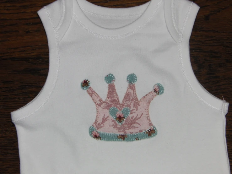 an image of a little girl's white tank top with crowns on it