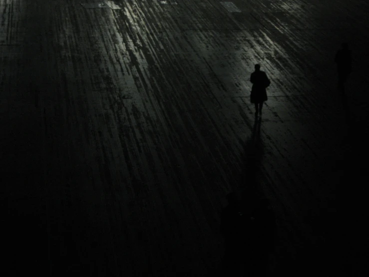 dark street with people walking down it and one walking in the dark