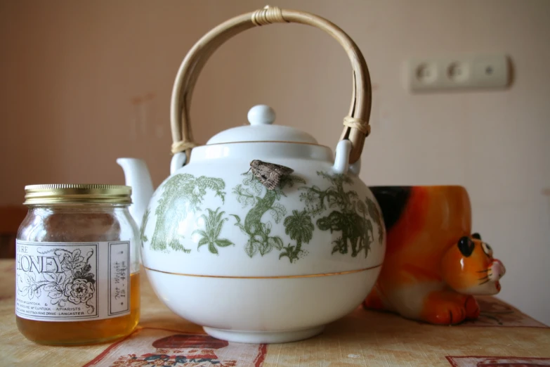 the teapot is next to a jar and honey jar