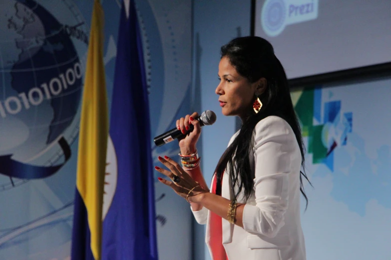 a woman speaking at a podium with flags