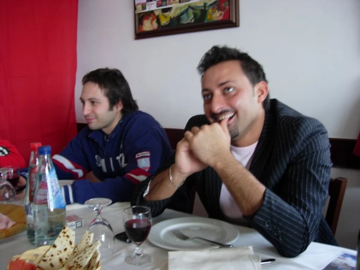 a couple of men sitting at a table with wine glasses