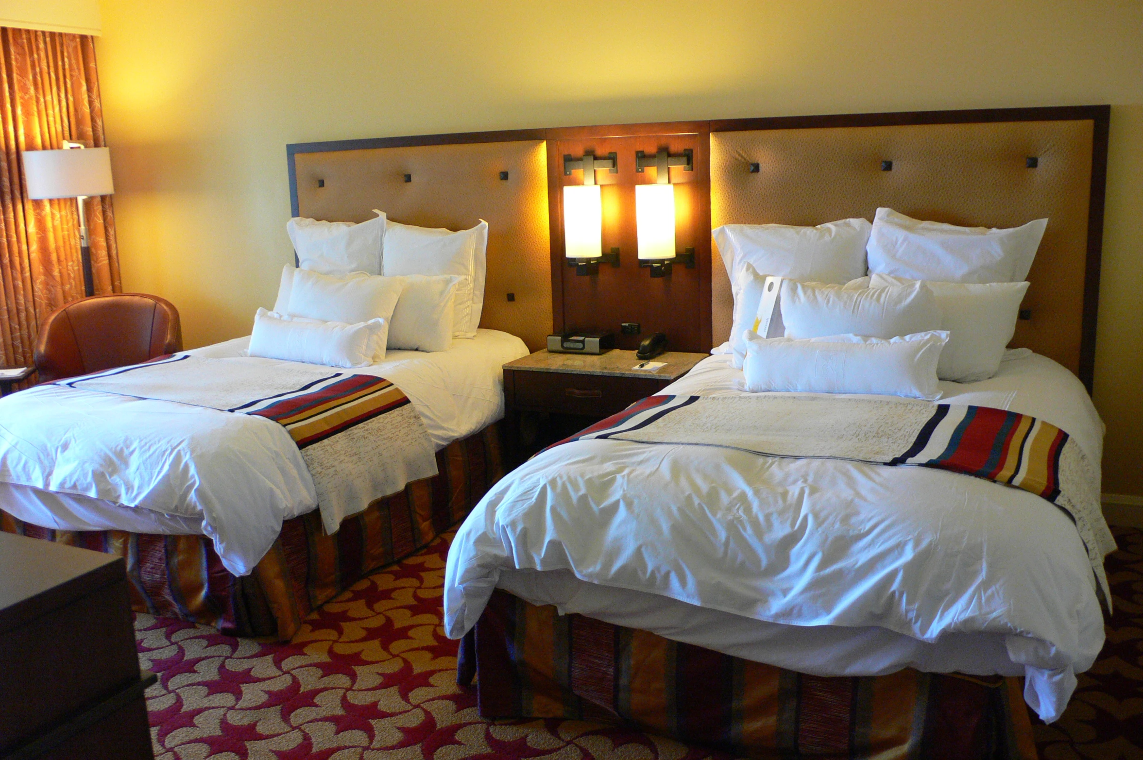 a el room with twin beds covered in white sheets and pillows