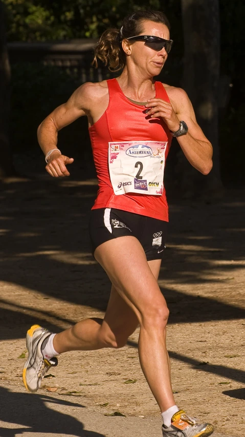 a woman running in a marathon next to trees