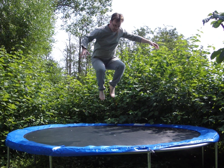 a person is jumping from a small blue trampoline
