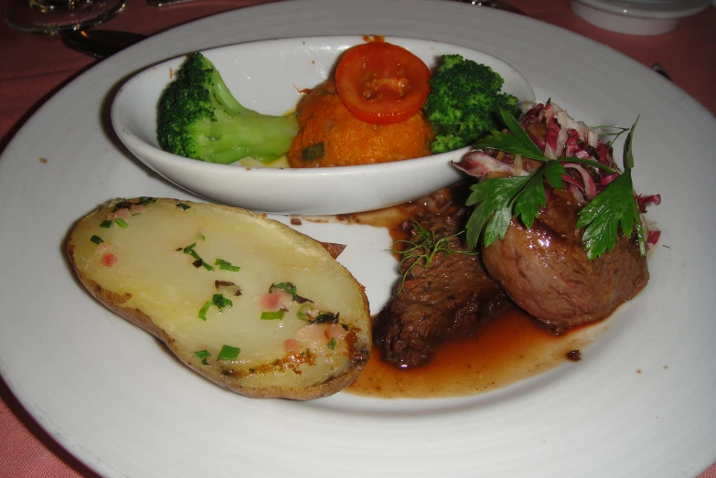 food on white plate with sauce on side, potatoes, carrots and broccoli