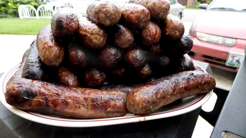 a plate with sausages on it sitting next to a car