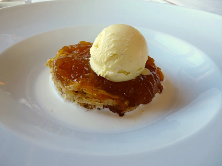 a dessert sits on a white plate with ice cream on top