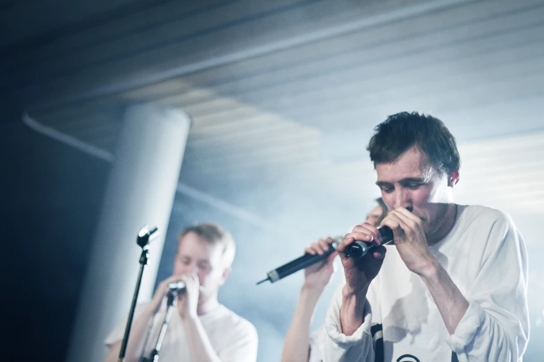 two men standing in front of microphones in a recording studio
