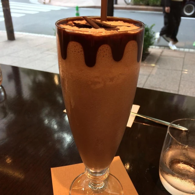 a chocolate milkshake sits in a clear glass