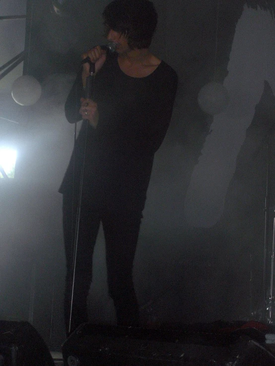 a man in black singing on stage while holding a microphone