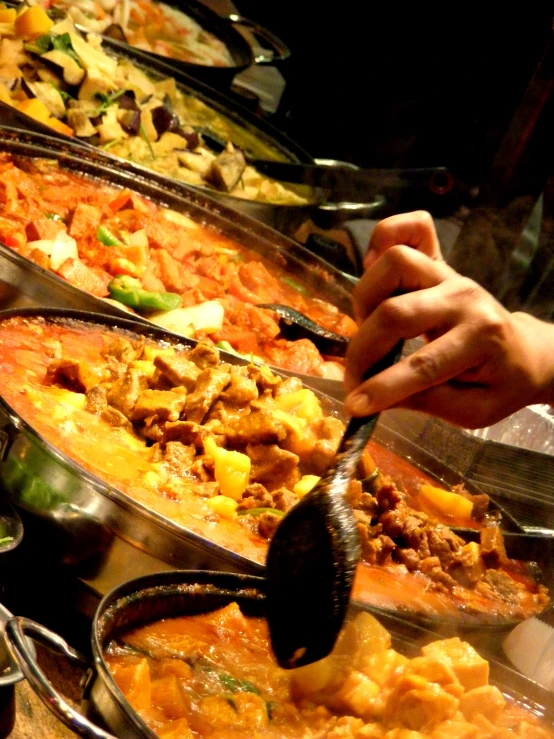 several people are serving themselves food in large trays