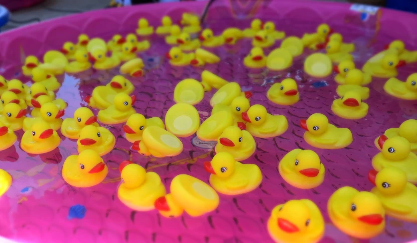lots of rubber ducks are lined up in a pink tub