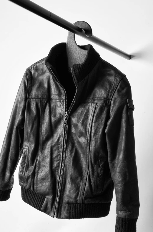 a black leather jacket hanging up against a wall