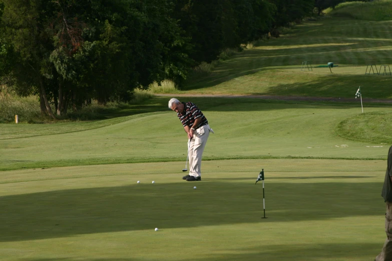 a person standing near a golf hole, putting a putt