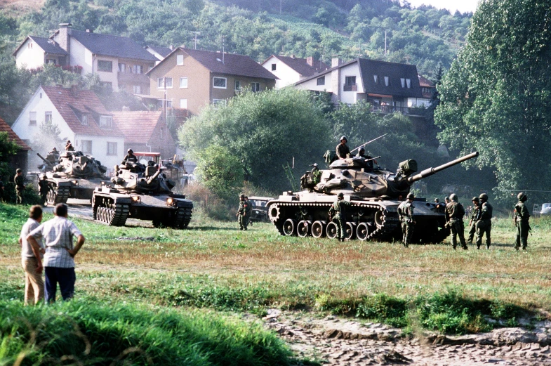 a group of people walking near military tanks