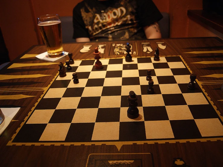 the person has a glass of beer next to his board game