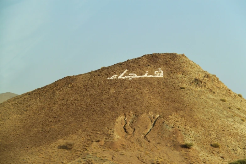 a very tall rocky hill with a written word on top