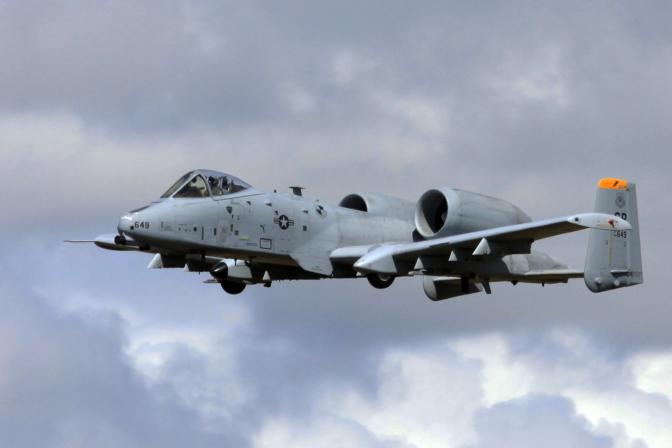 a white jet in the sky with clouds behind it