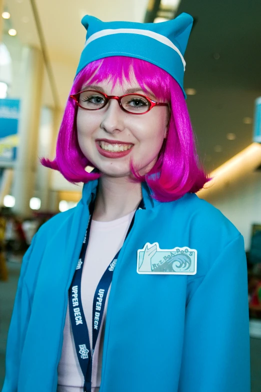 a woman with pink hair and a blue jacket is smiling