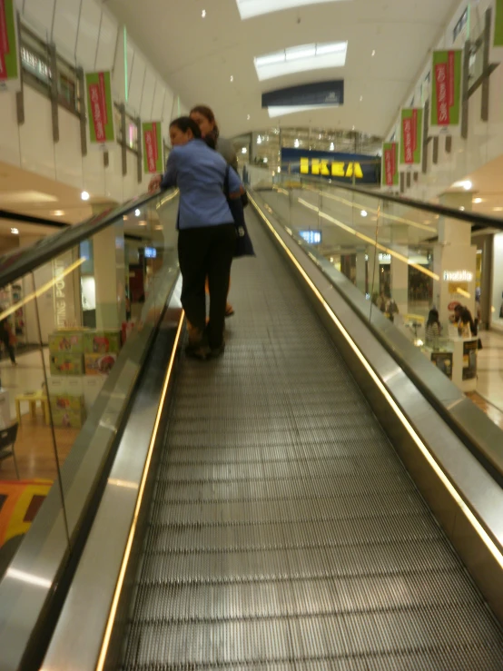 two women are walking down an escalator in a mall