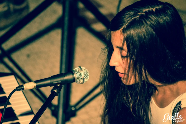 woman singing in front of microphone on stage with musical instrument