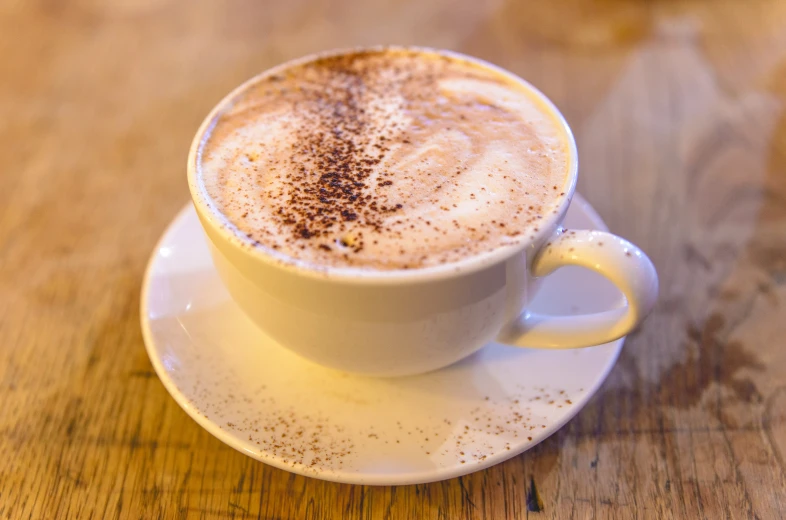 a cappuccino on a saucer with cinnamon powder in the shape of a heart