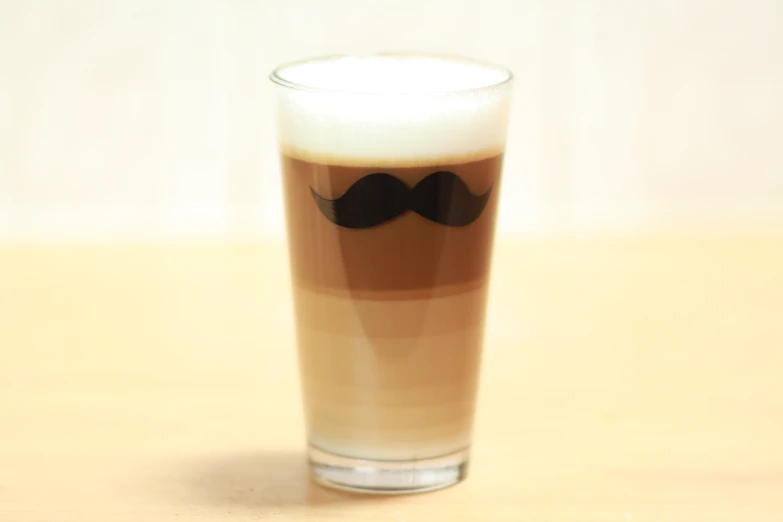 a tall glass with some liquid and a mustache