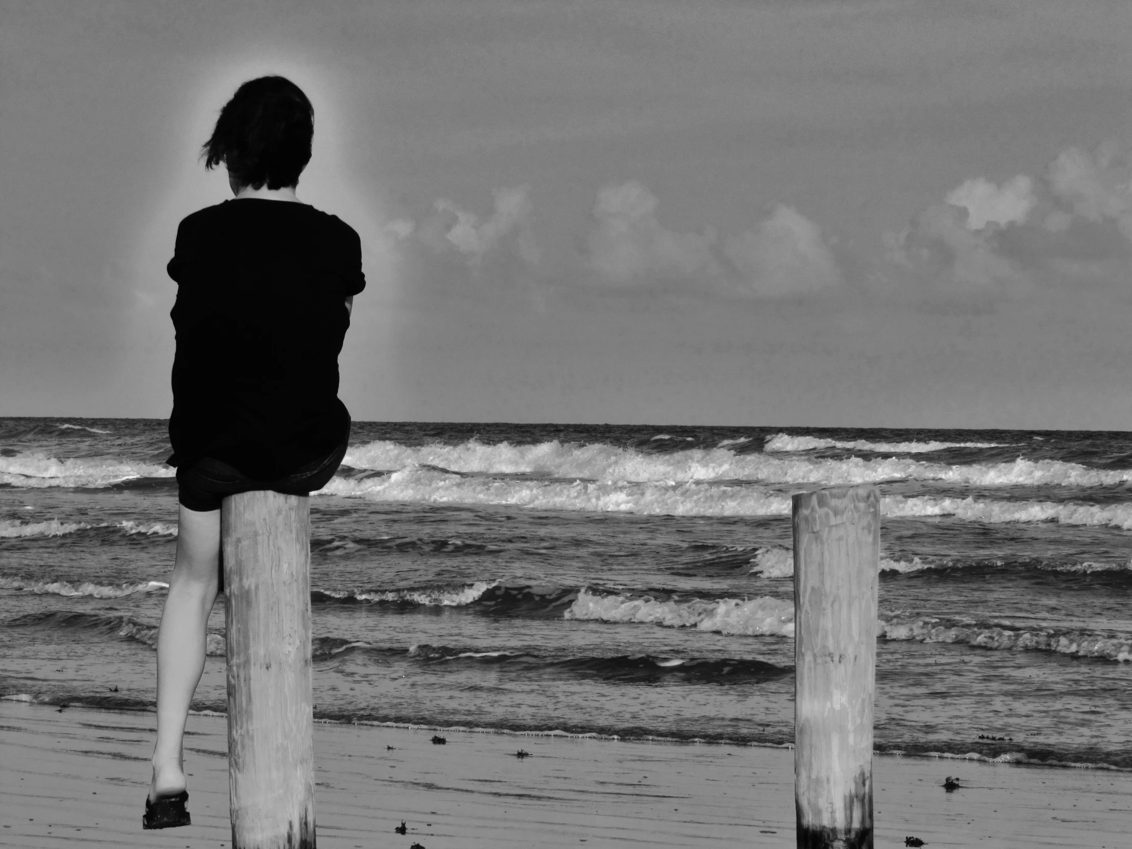 the person is sitting on the post on the beach