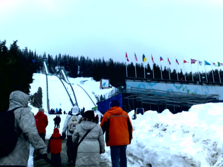 a group of people in winter jackets stand around a pile of snow