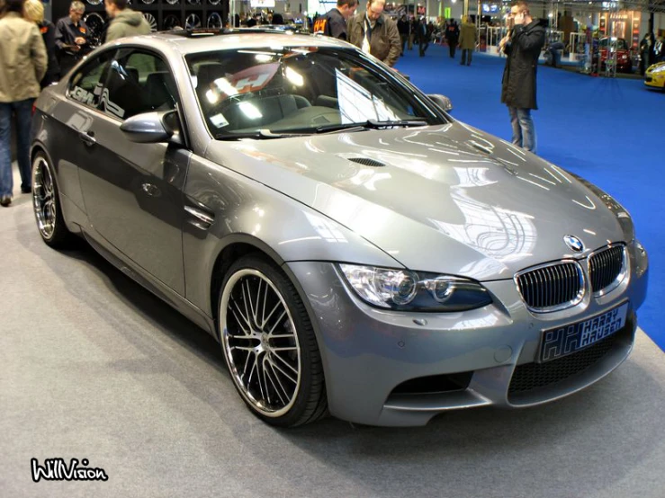 grey car on display during a show with people around