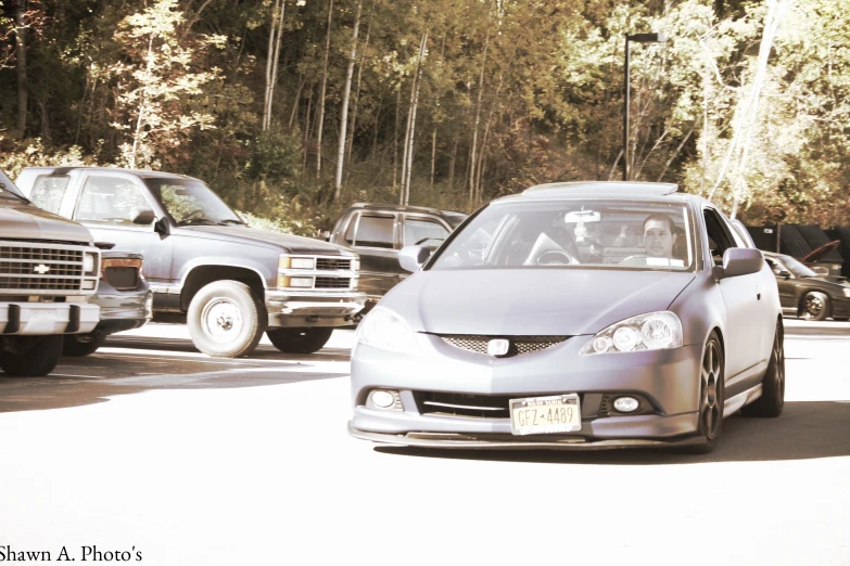 a silver car in a parking lot with trees in the background