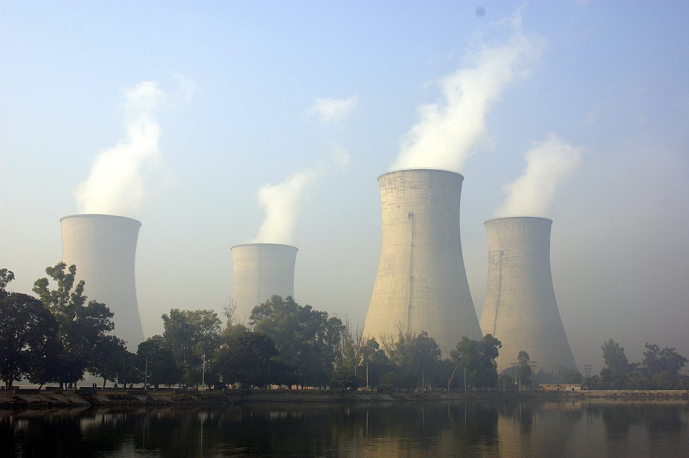 a large cooling plant in the distance surrounded by trees