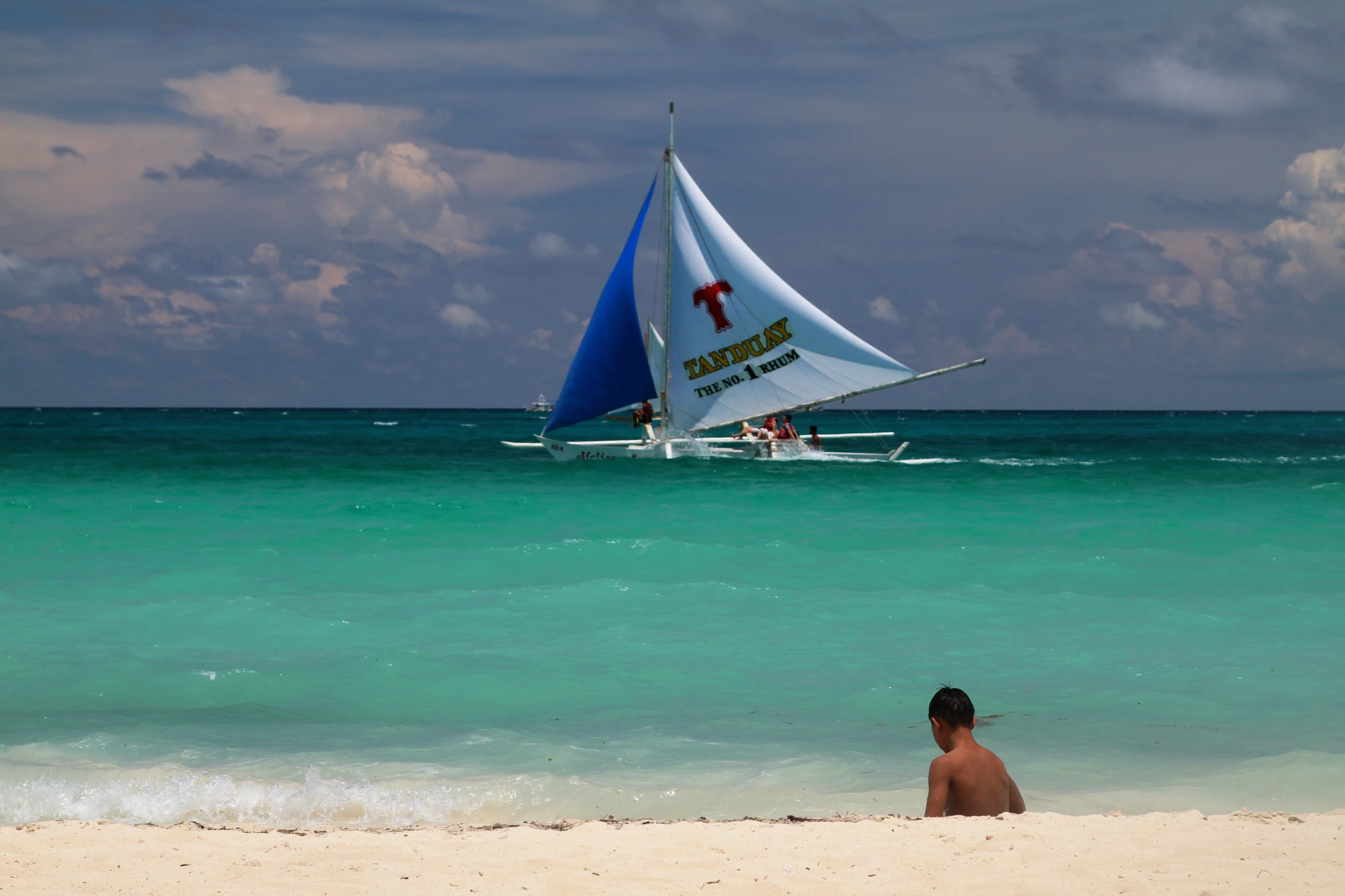 a person on a beach with a sailboat in the distance