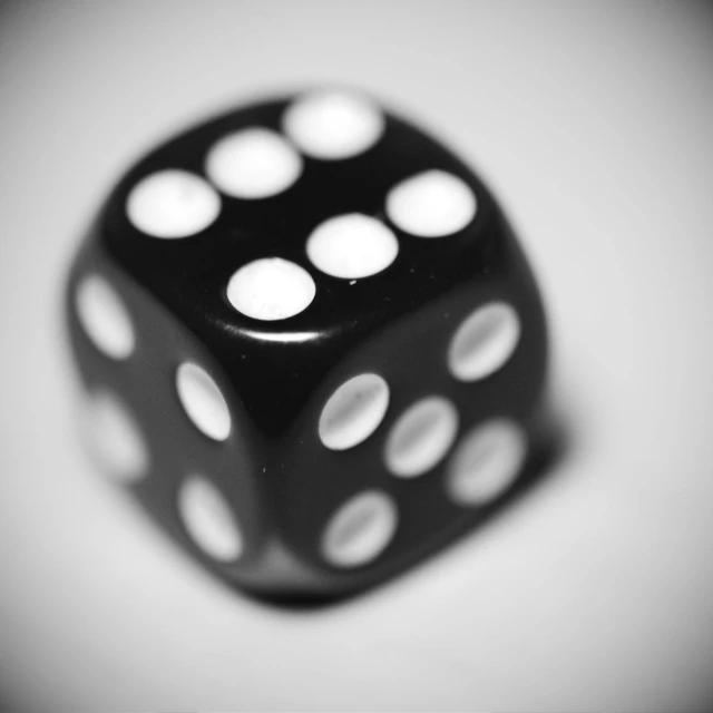 a black dice with some white spots on it