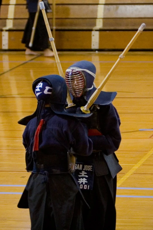 two ken fighters on a court one is holding a wooden stick