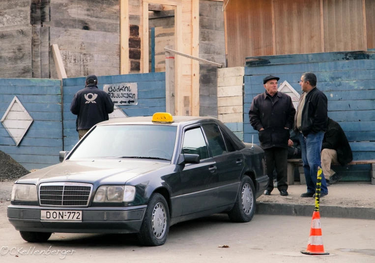 a car stopped at a construction site with several men standing around