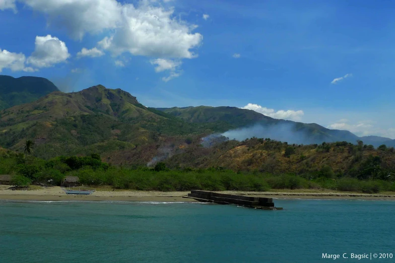 a very big mountain by the water and clouds