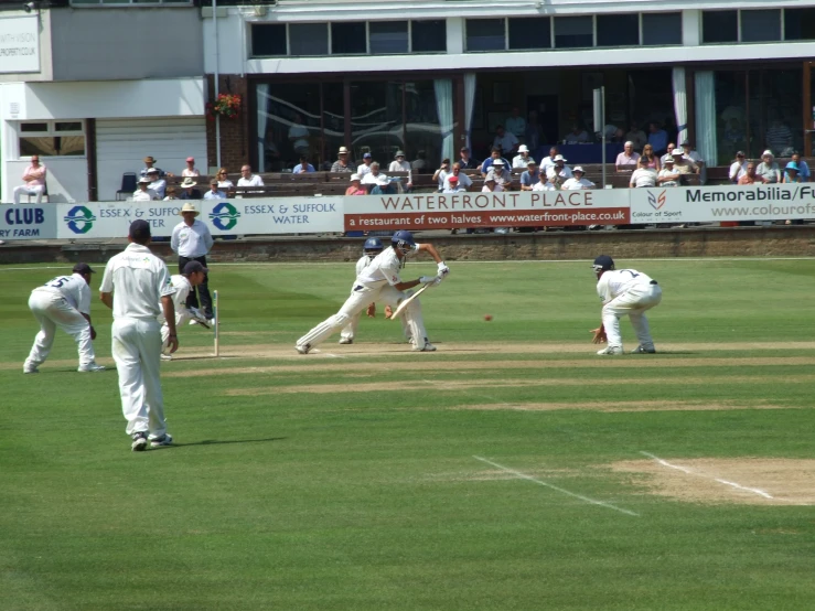 many people on the field playing cricket and people in the stands watching