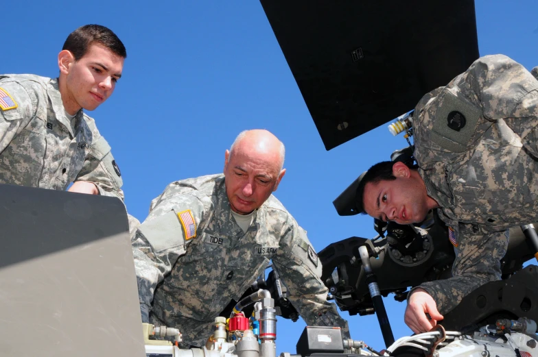 two men in uniform with electronics next to a machine