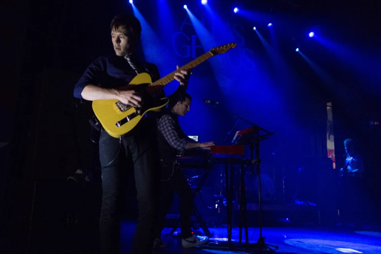 a man playing guitar in front of blue lights