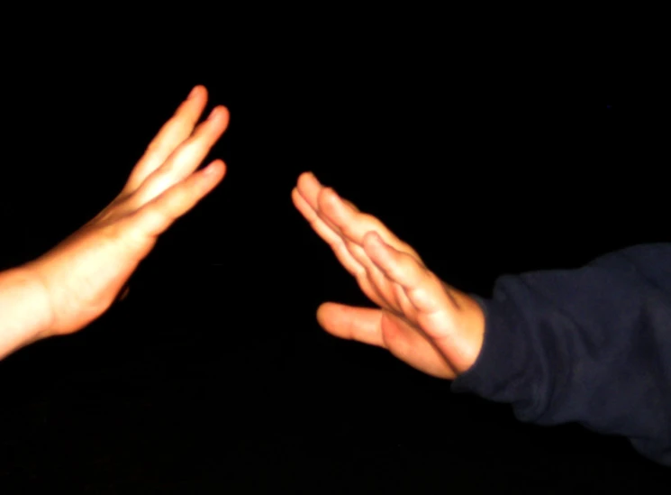 two hands reaching up for soing with a dark background