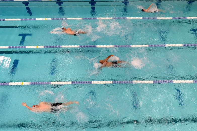 men swim in a pool while the other man watches