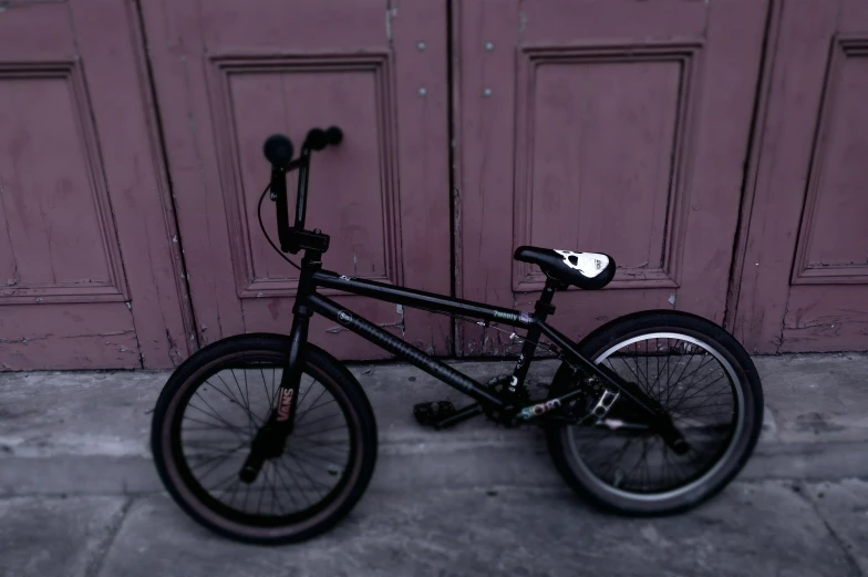 the black bicycle is parked in front of a door