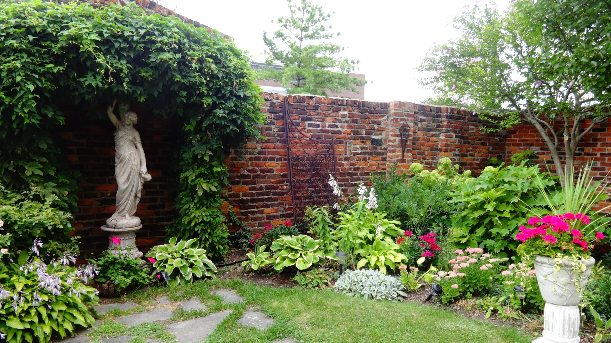 garden scene showing lawn with flowered area and statues