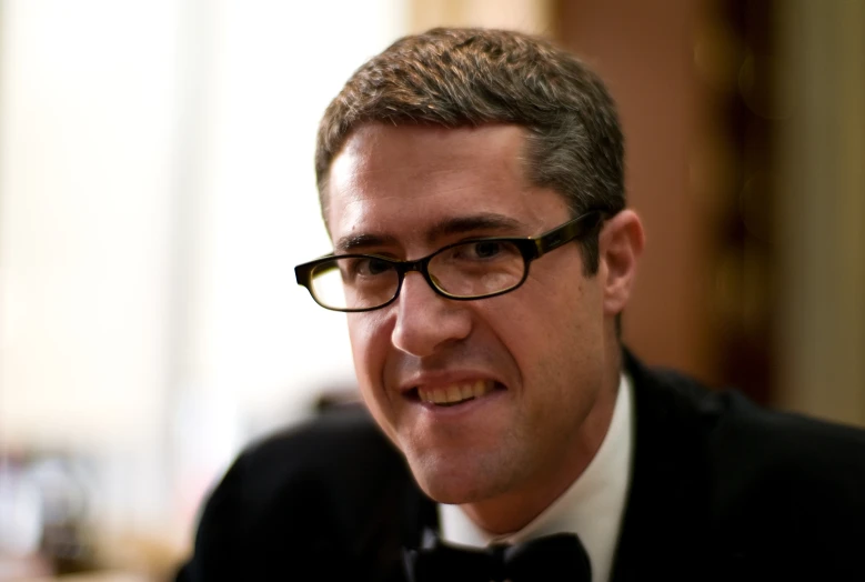 a man in glasses looking forward while wearing a bow tie