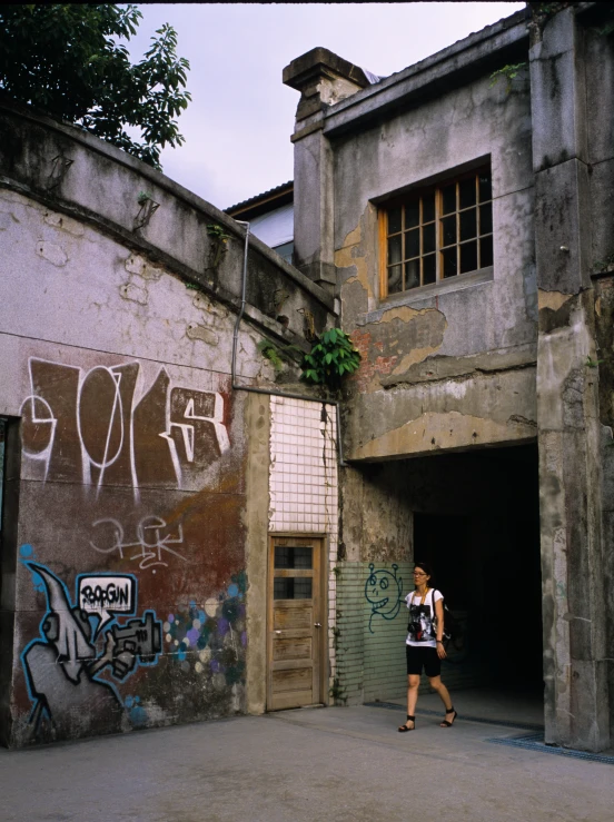 the lady walks away from the building with graffiti on the walls