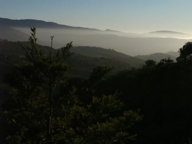 there is fog rolling over a mountain in the distance