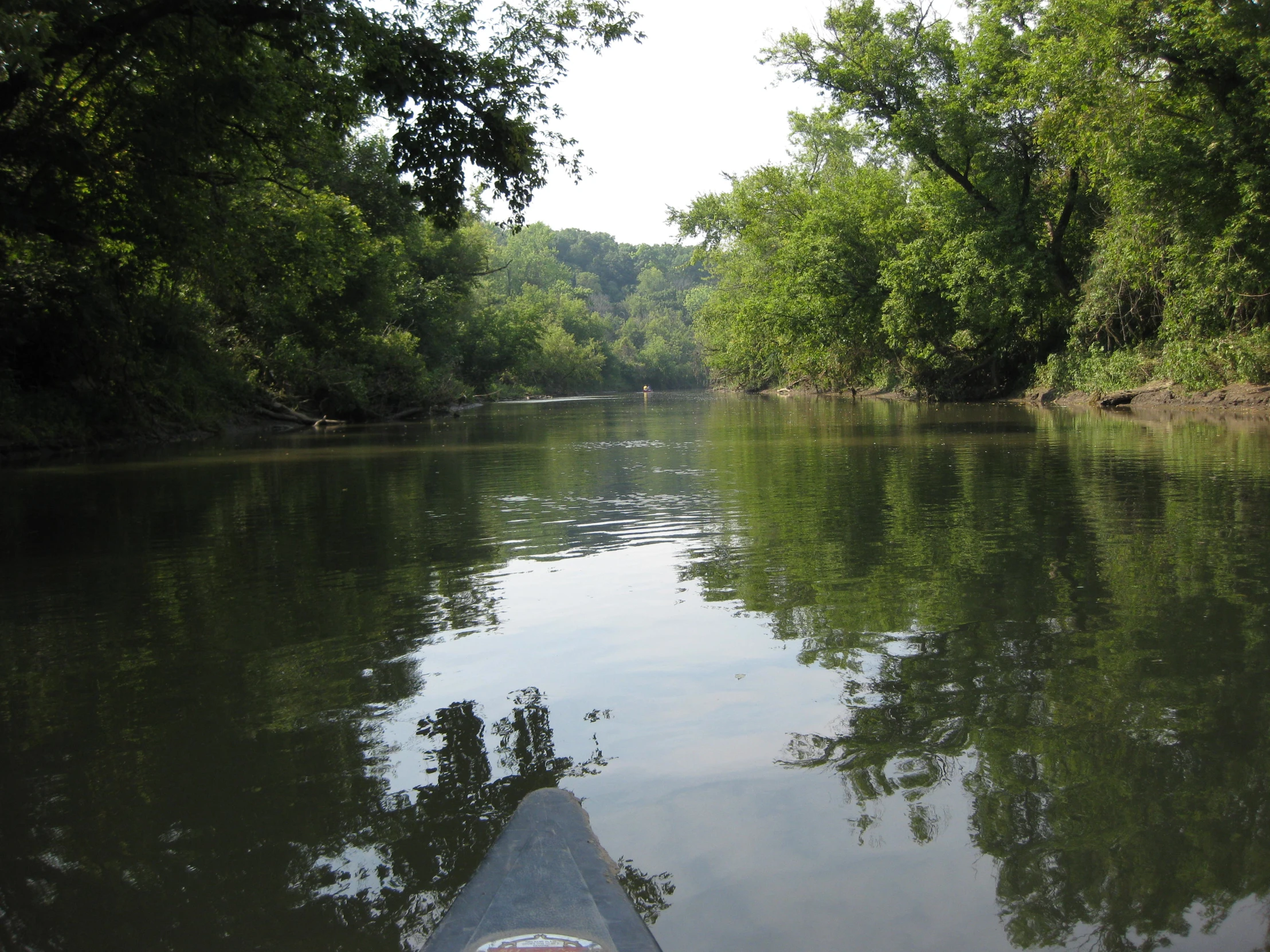 a small boat floating down a river surrounded by lush green forest