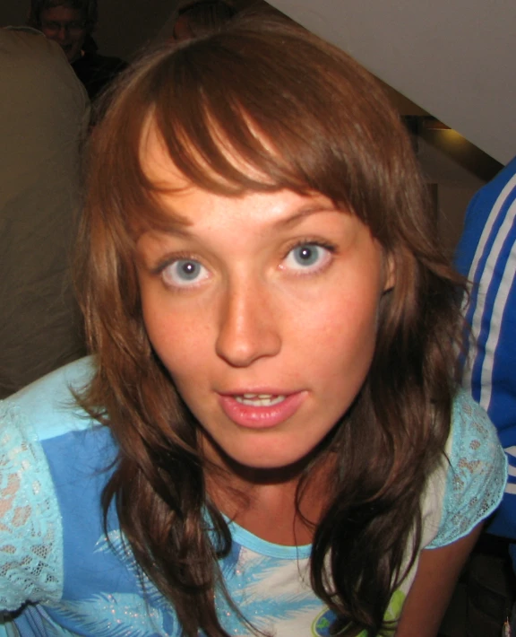 a woman in a blue shirt with her head tilted back